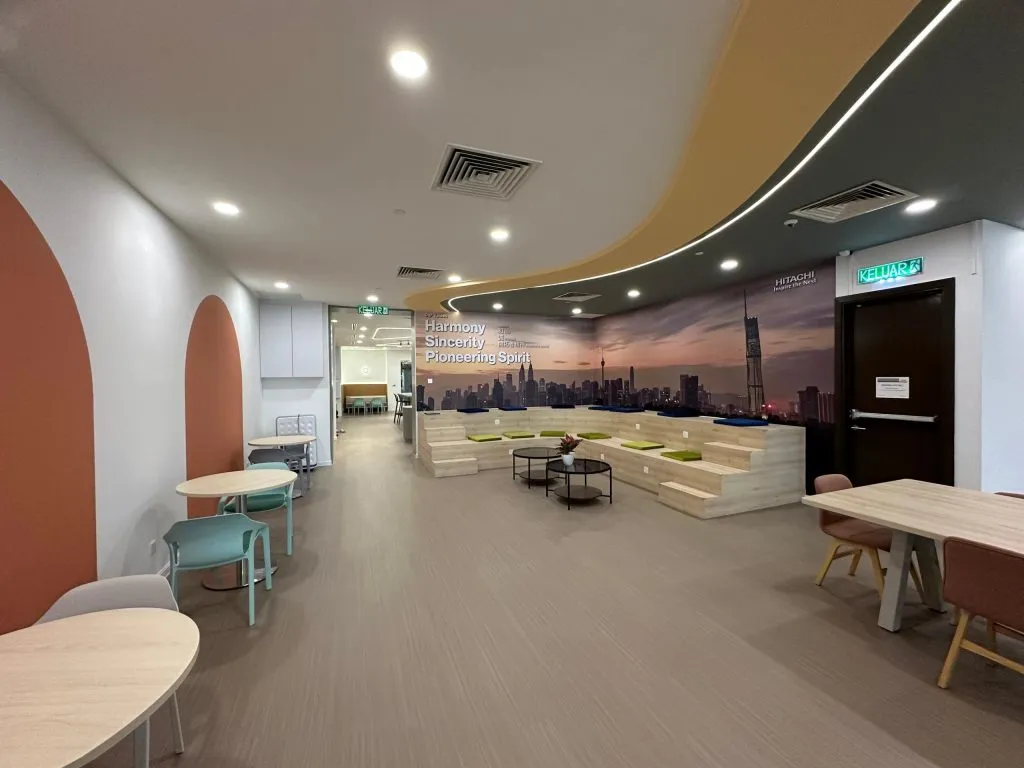 An open office floor with breakout seating, tiered benches and a city-skyline mural