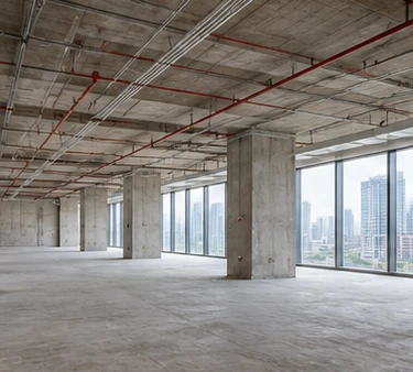 A bare shell-and-core floor with exposed concrete ceiling, columns and services
