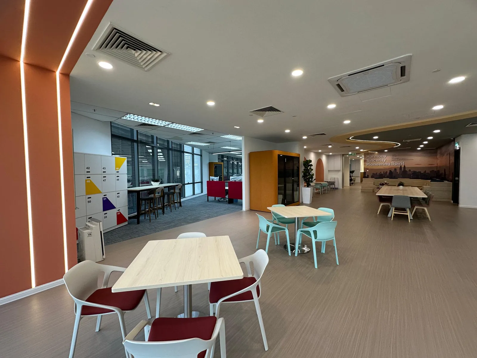 Office pantry with café tables, breakout seating and a city-skyline mural